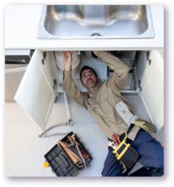 tech making a repair under a kitchen sink cabinet