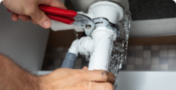 Plumber tightening leaky pipe with wrench